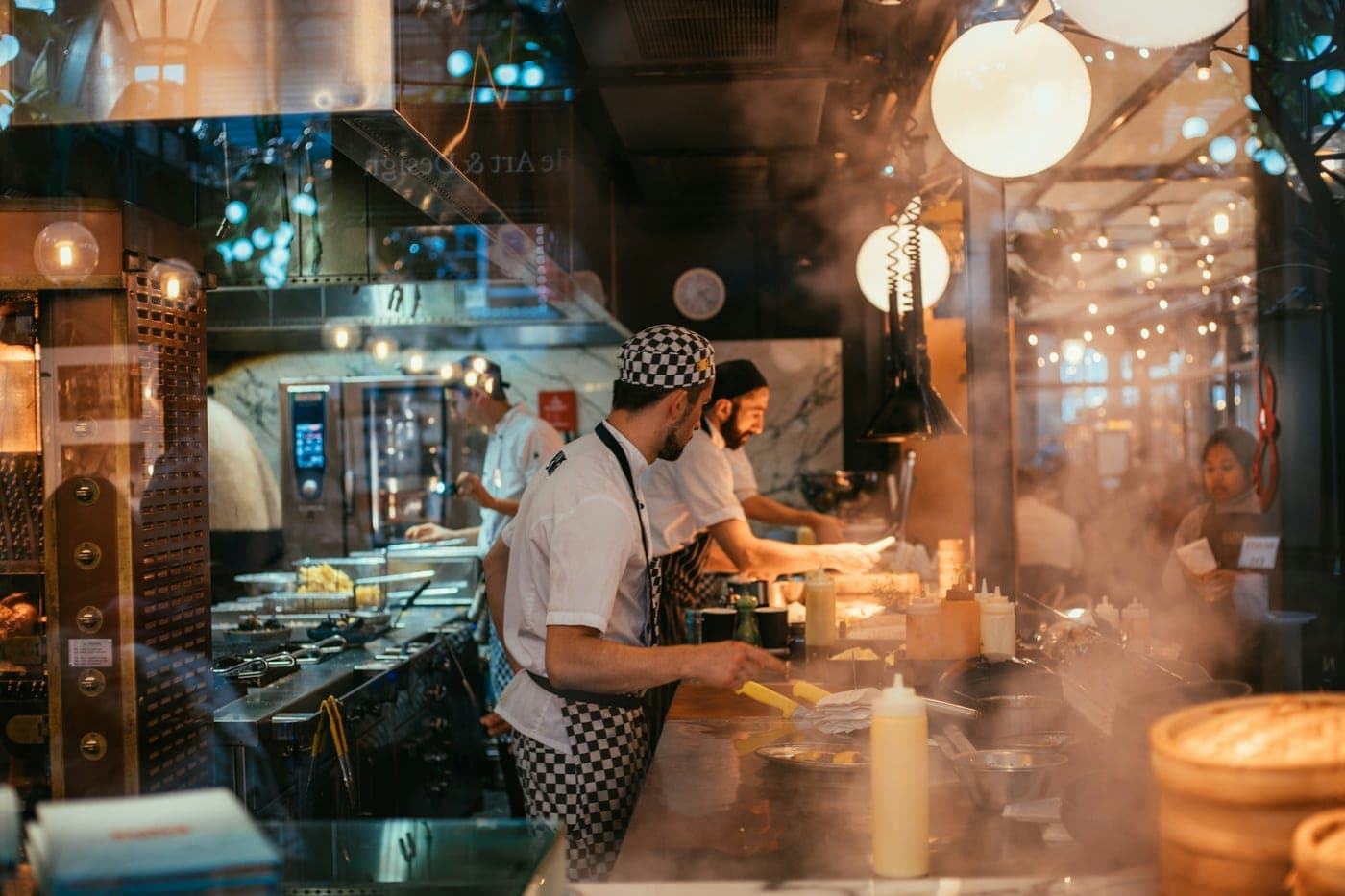 Cozinheiros preparando pedidos em uma cozinha de restaurante movimentada